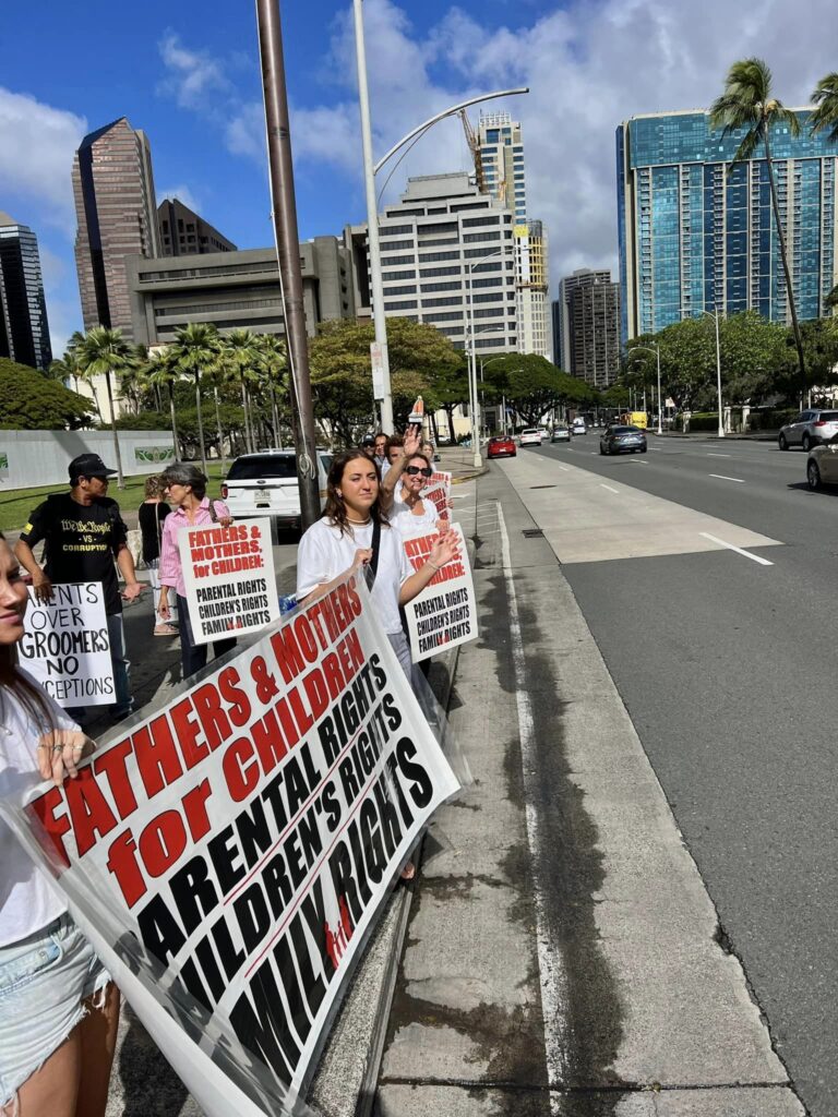 A supporter holding a Fathers and Mothers for Children sign beside a Honolulu street
