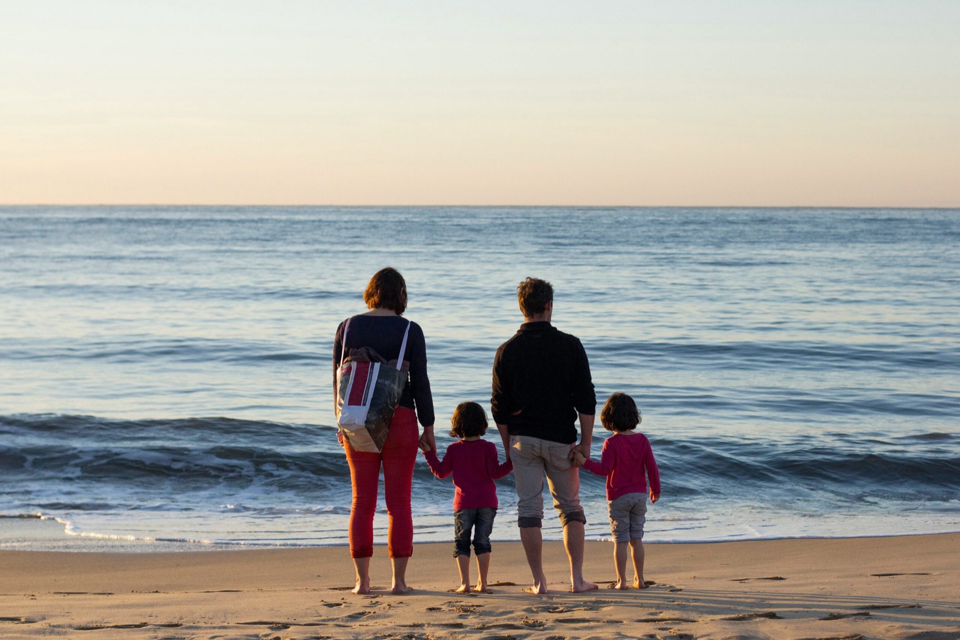 A family standing together on the beach, looking out at the ocean